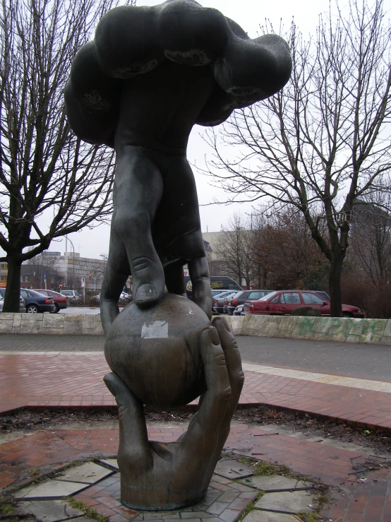 statue of a man carrying an elephant sitting on top of a ball