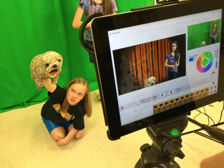 two small children wearing different costumes sit next to a monitor displaying video