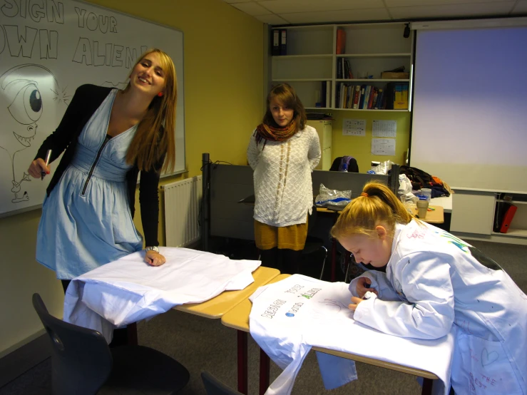 two s sit at desks writing on white paper