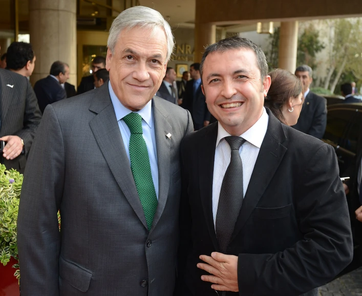 two men standing next to each other in suits