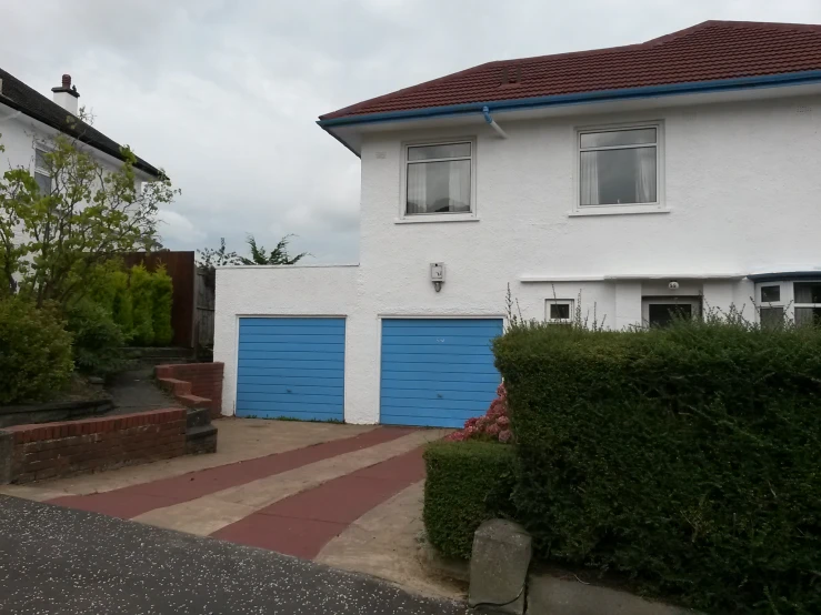 a two story white house with blue garage doors