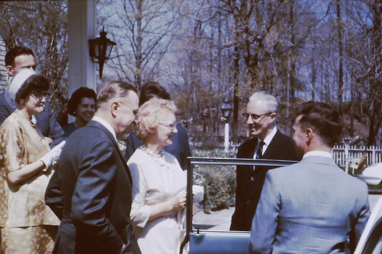 an old couple having a conversation while standing next to a car