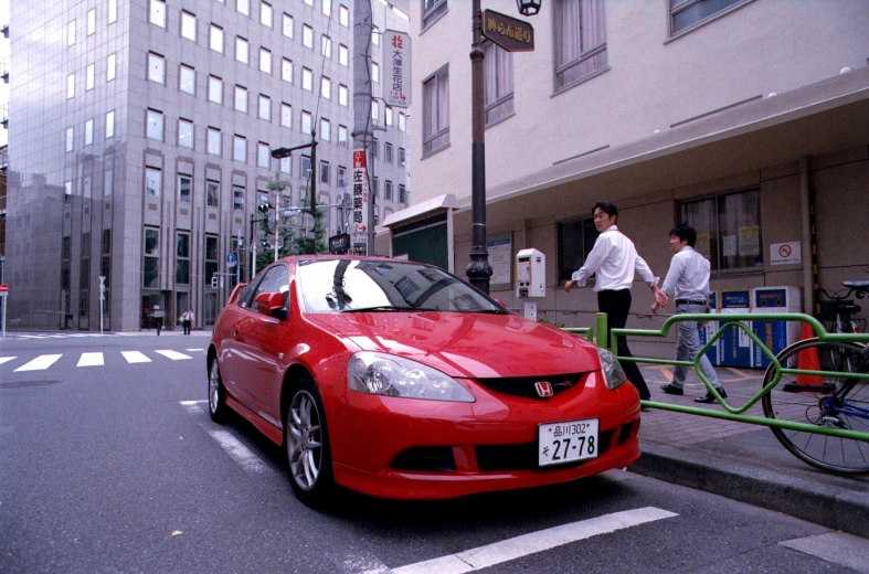 a red car in front of a metal rail and bike rack
