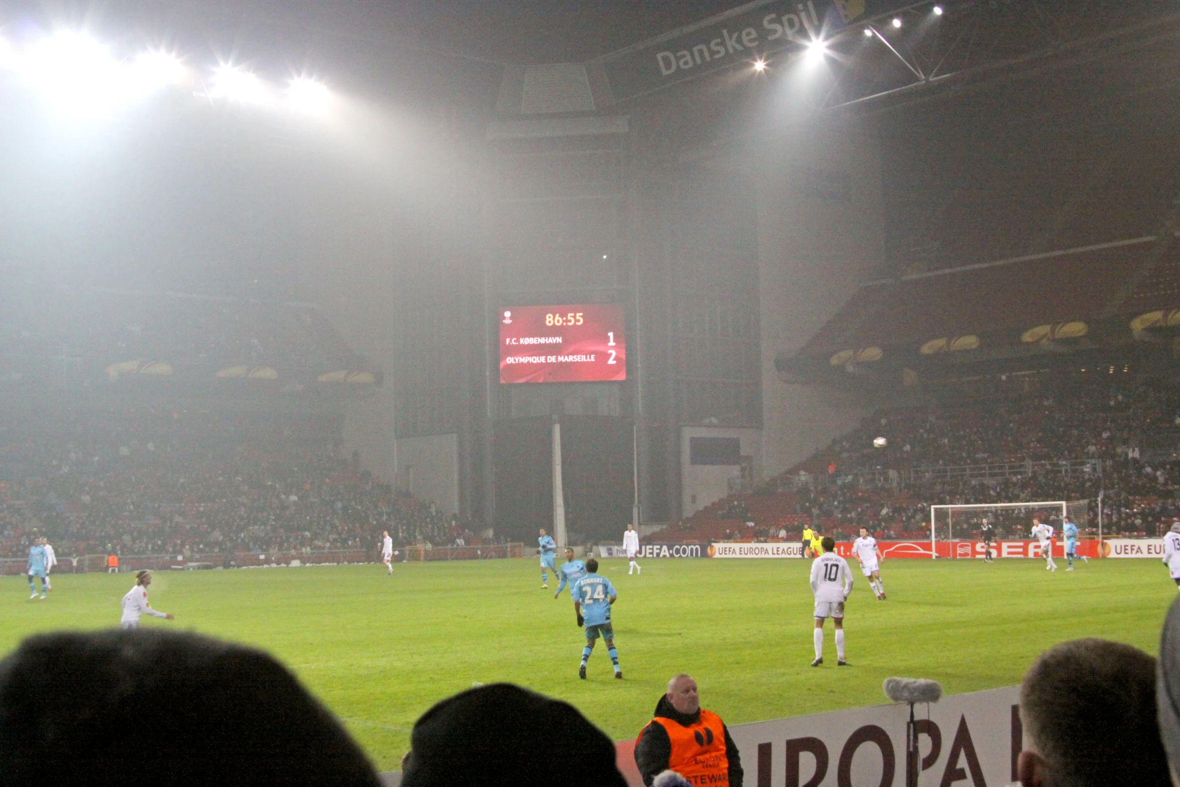 several men play soccer on a field as fans watch