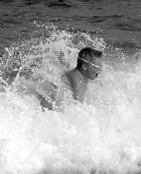 a boy swimming with his arm in the water and breaking wave