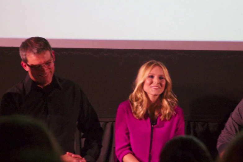 two men and a woman standing in front of a screen