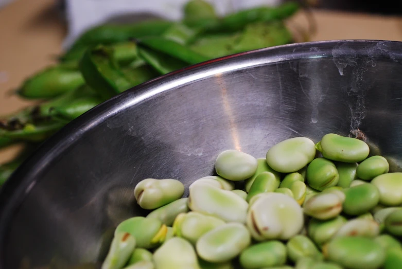 a metal bowl full of sprouts sitting on top of a counter