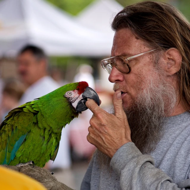 a man holding a parrot with his hand on it