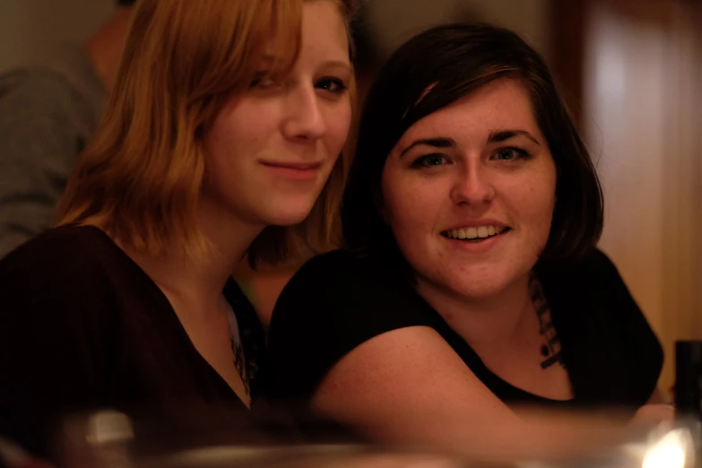 two women sitting side by side while holding wine glasses