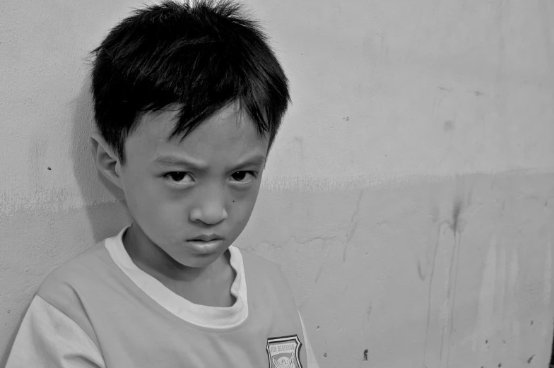 a small boy wearing a sweater in front of a wall