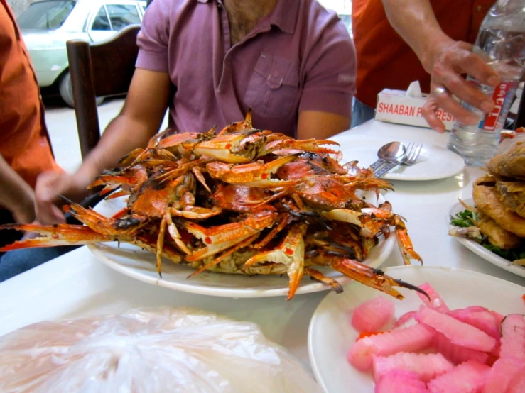 large plate full of cooked crabs next to small plates of cooked vegetables