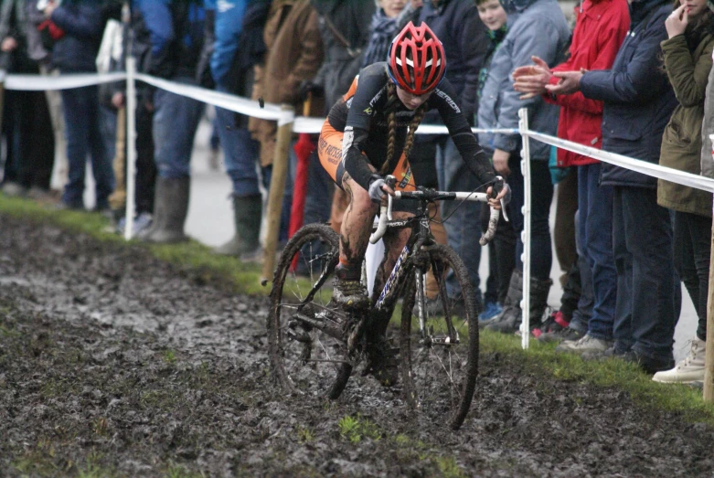 a man on a bike rides through mud