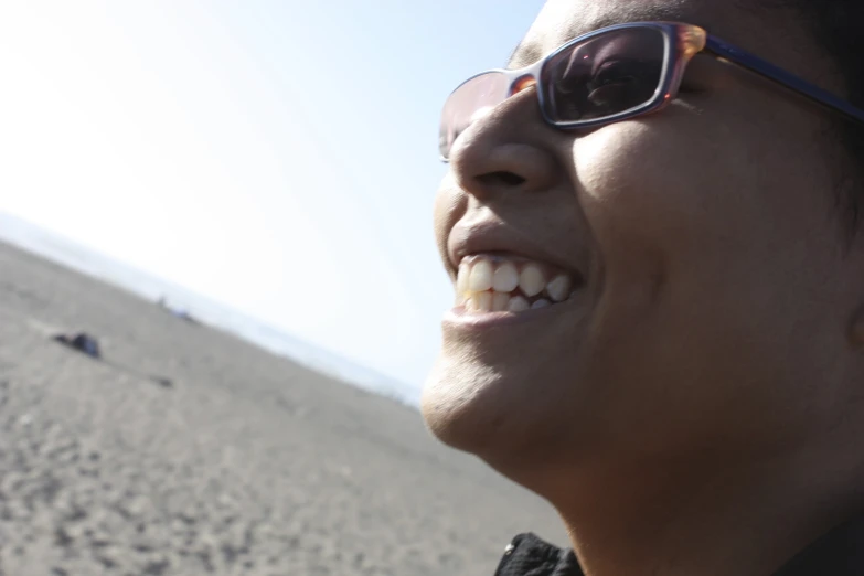 a young woman smiles at the camera on a beach