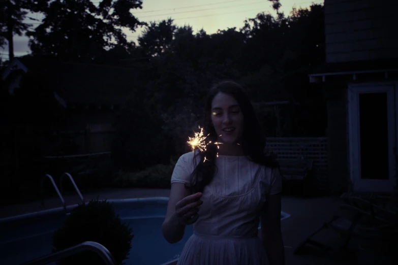 the woman smiles as she holds a sparkler