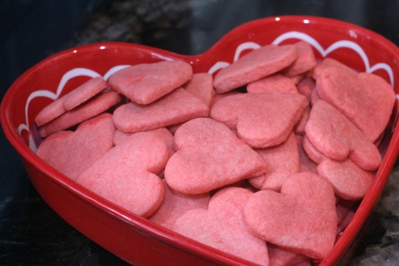 a red heart shaped bowl filled with hearts