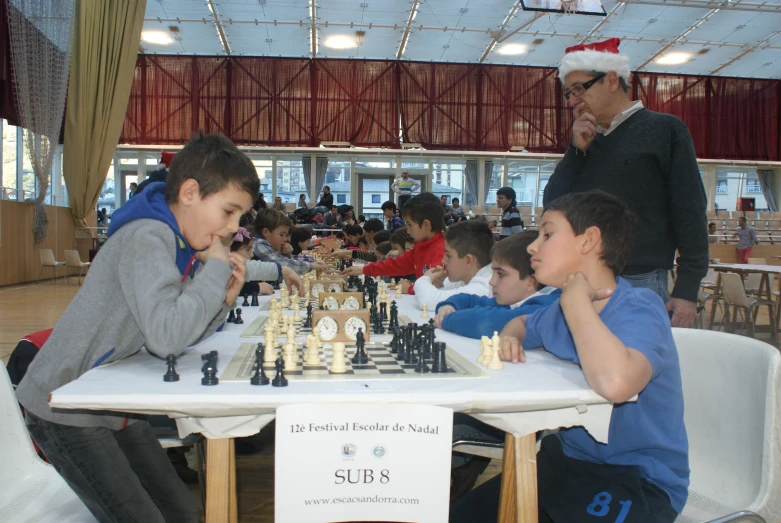 s sitting around the tables at an indoor chess tournament