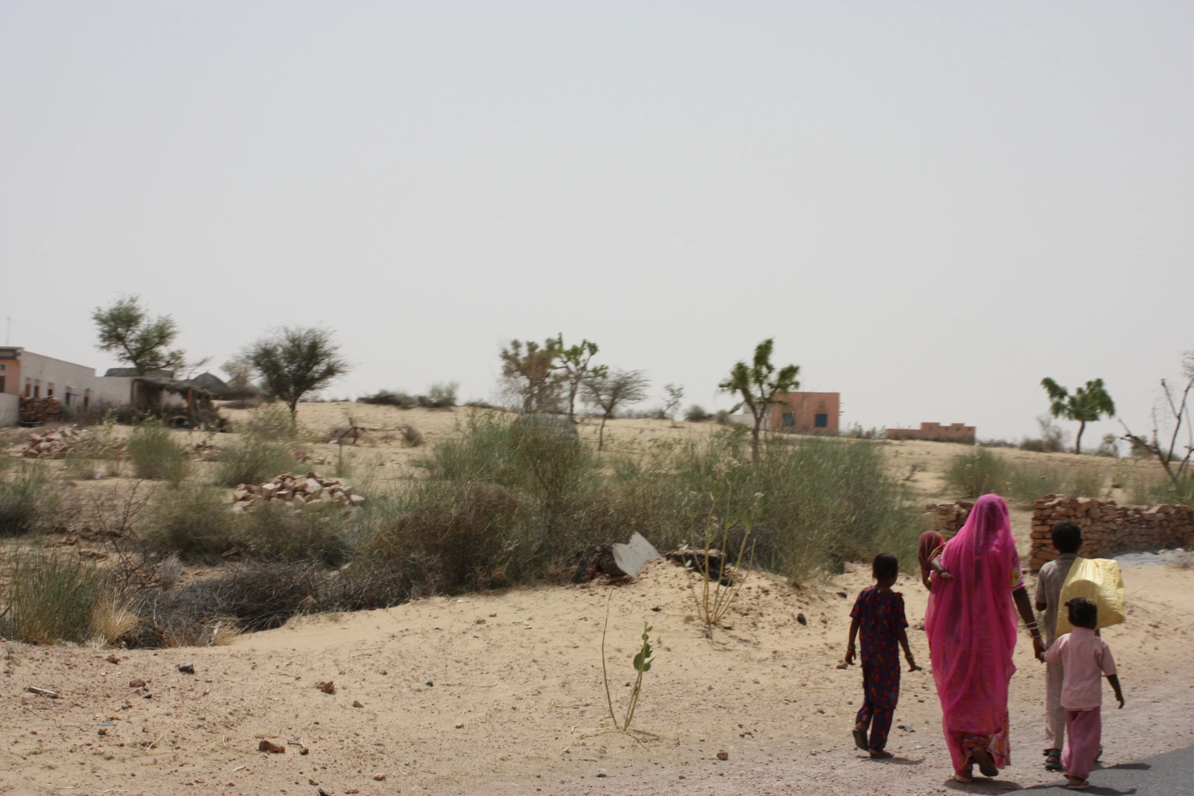 some children are walking down the road in the desert