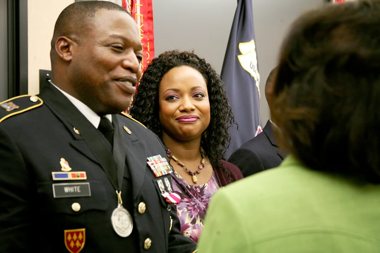 a man and woman talking to people wearing army uniforms