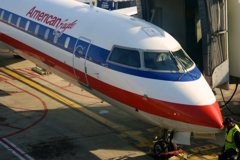 a man stands next to a plane that is red, white and blue