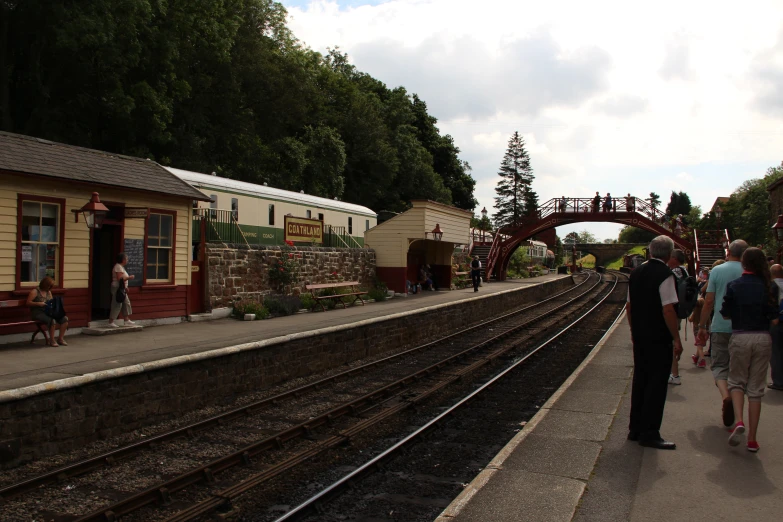 people are walking near the train tracks in a station