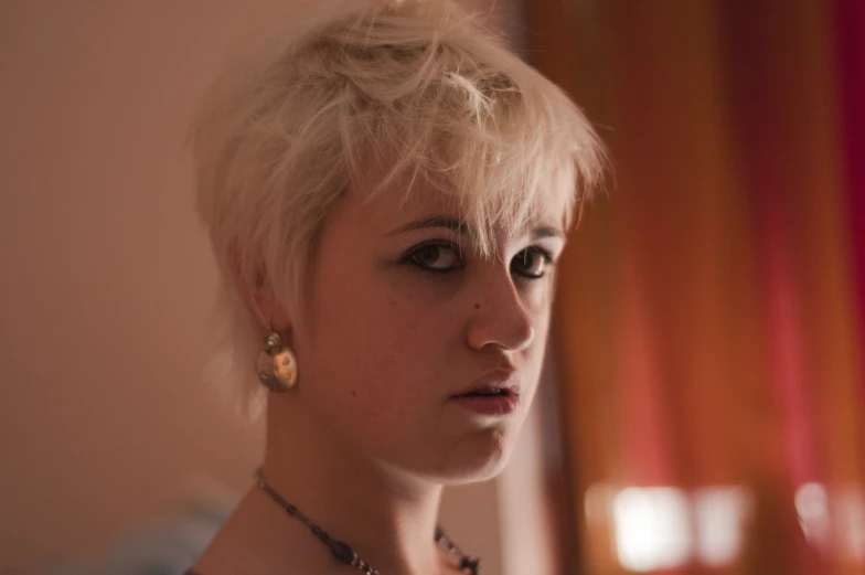 a woman is wearing pearls and looks into the camera