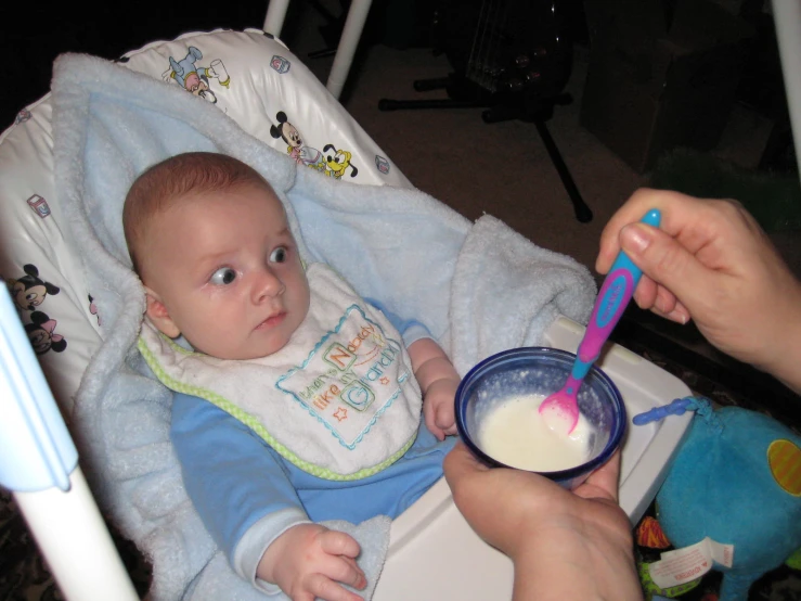 a baby with a spoon in it sitting in a seat