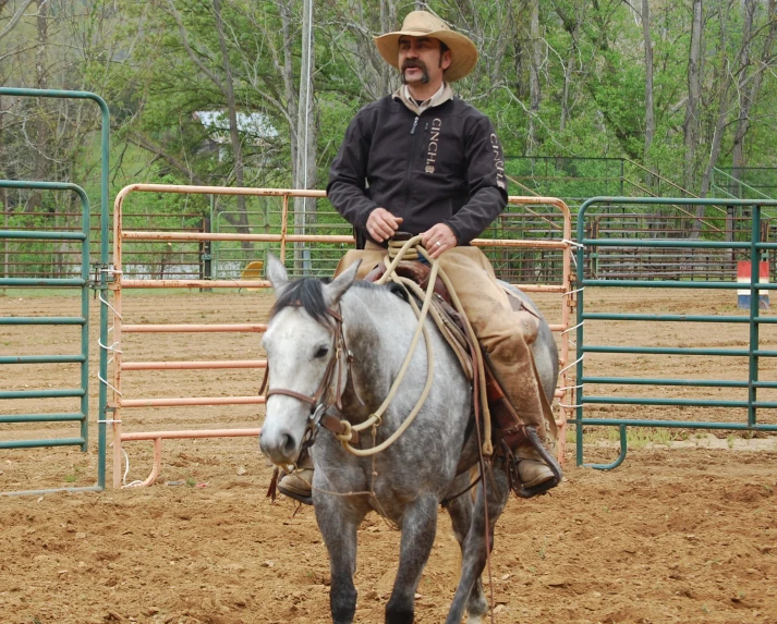 the cowboy smiles as he rides a horse