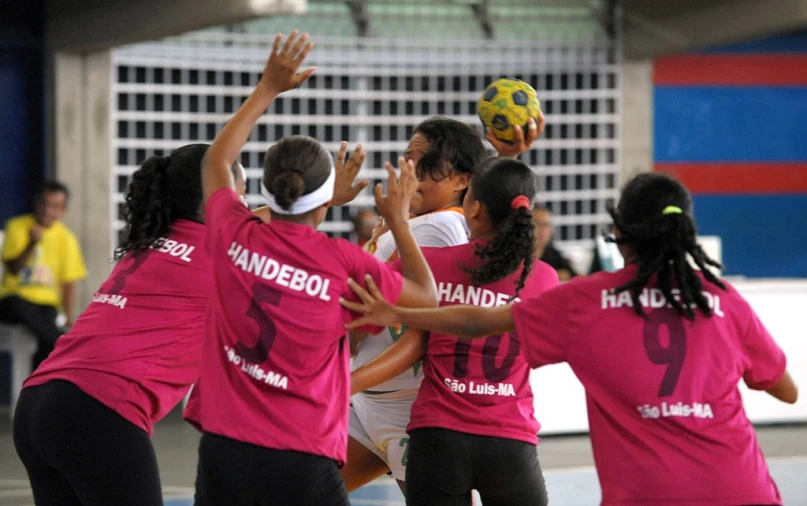 several girls in pink shirts are playing with a soccer ball