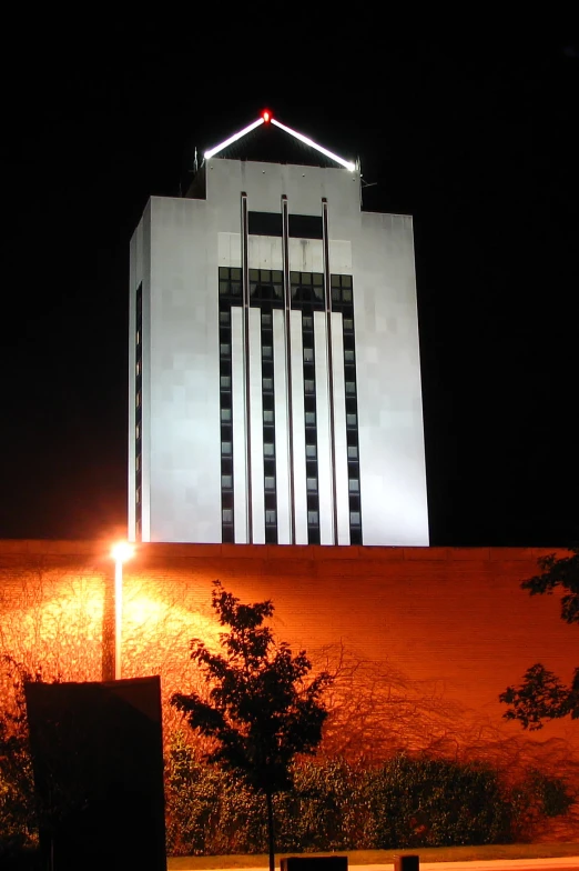 a tall building illuminated up at night with a lighted roof