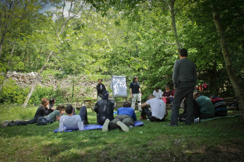 a group of people sitting on top of a green field