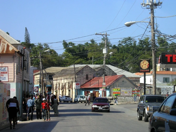 people and cars are driving down a street on a sunny day