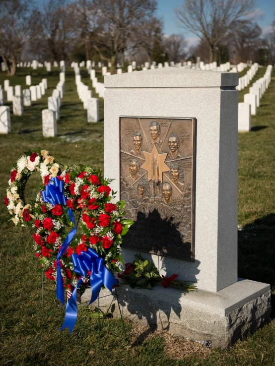 a wreath sits in the grass beside a grave