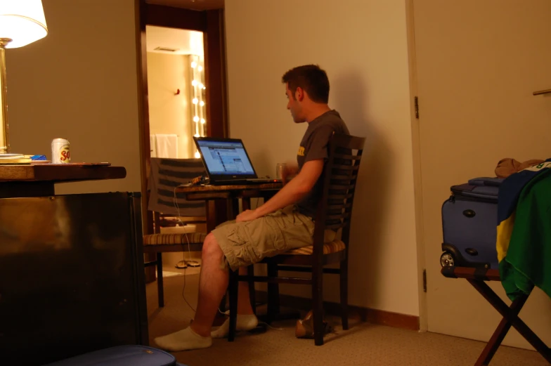 the man is sitting in the room using his laptop