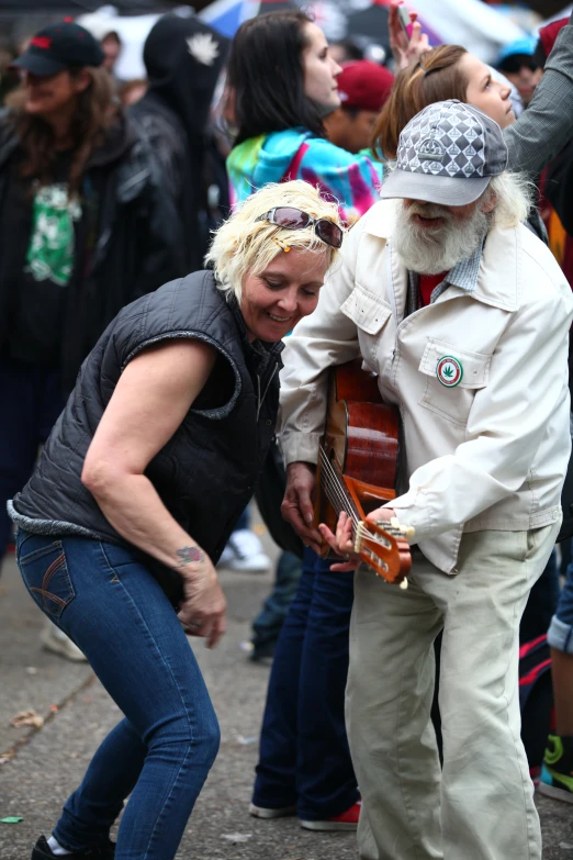 a woman playing an acoustic guitar next to a man with a fake beard