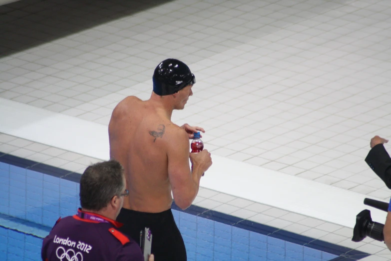 a shirtless male is holding a camera near a pool