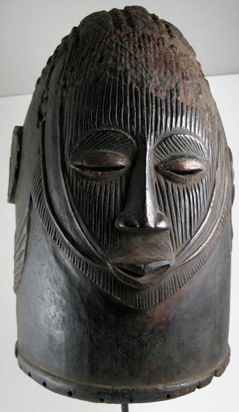 an african sculpture depicting a man's face and his head on a stand