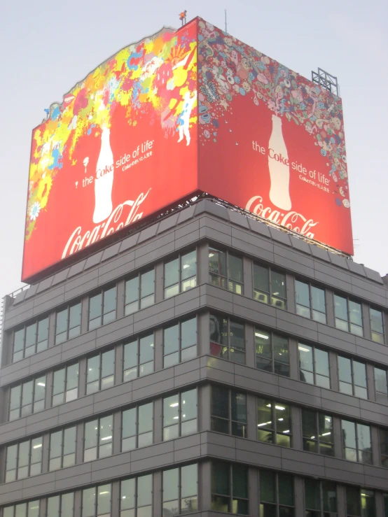 a tall building has coca - cola advertit on the top