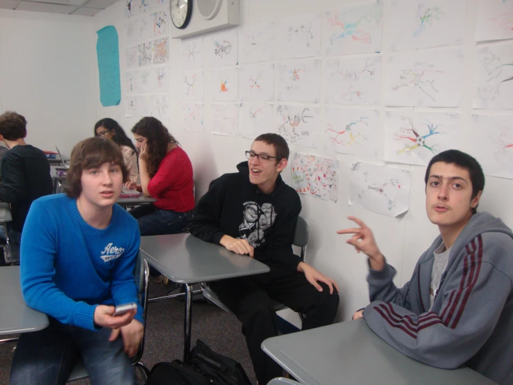 three people in a school room with many wall decorations