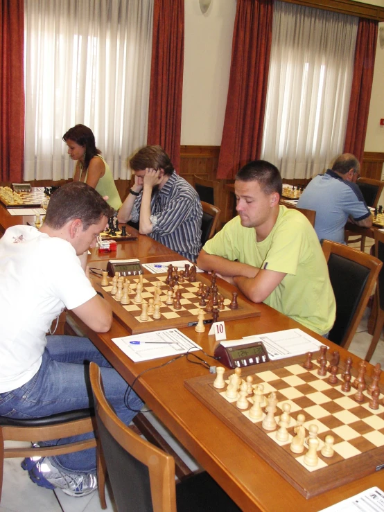 several people are sitting at tables playing chess