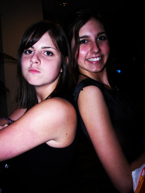 two beautiful young women hugging each other with an alarm clock in the background