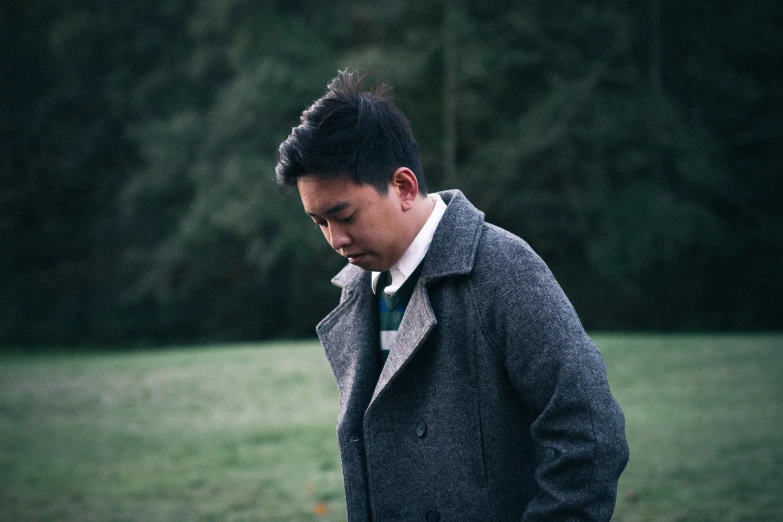 a man in gray jacket and tie standing by trees