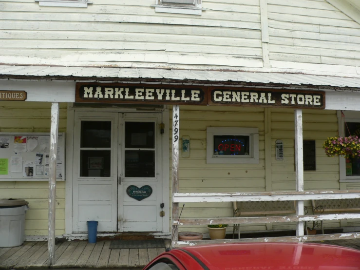 a red car is parked outside a general store