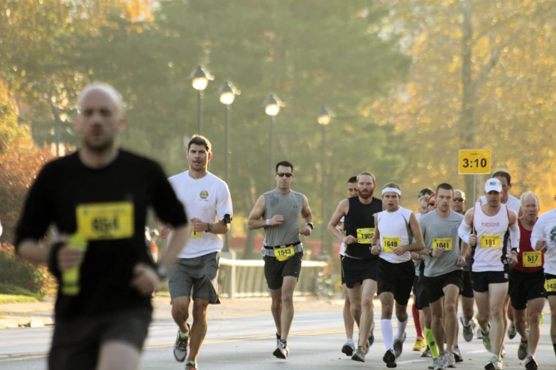 a crowd of men run down the street in a marathon