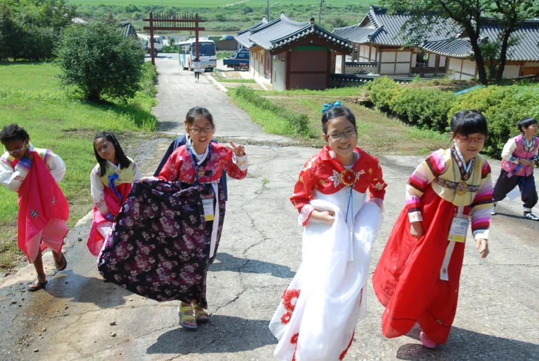 children in brightly colored costumes walking down a path