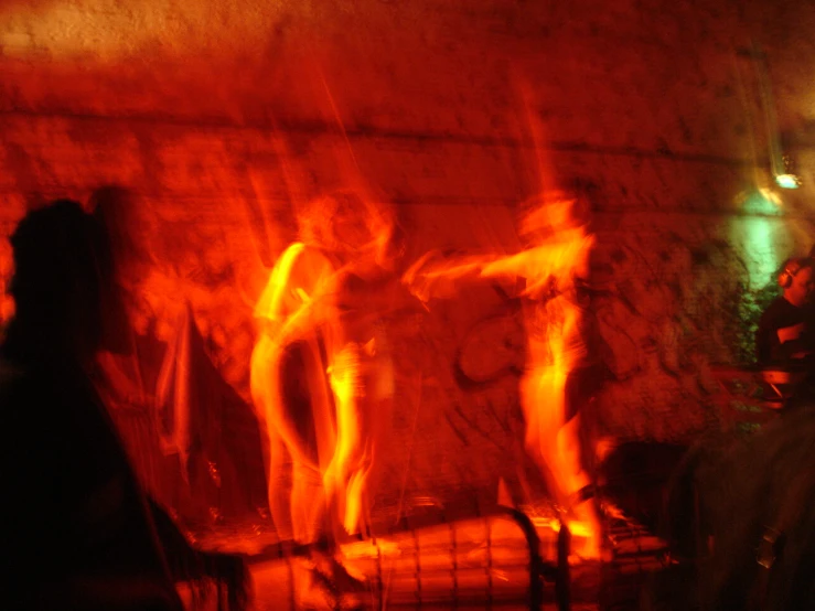 a group of people standing around a fire place with brick walls and floor