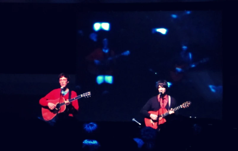 two male musicians are playing together on stage