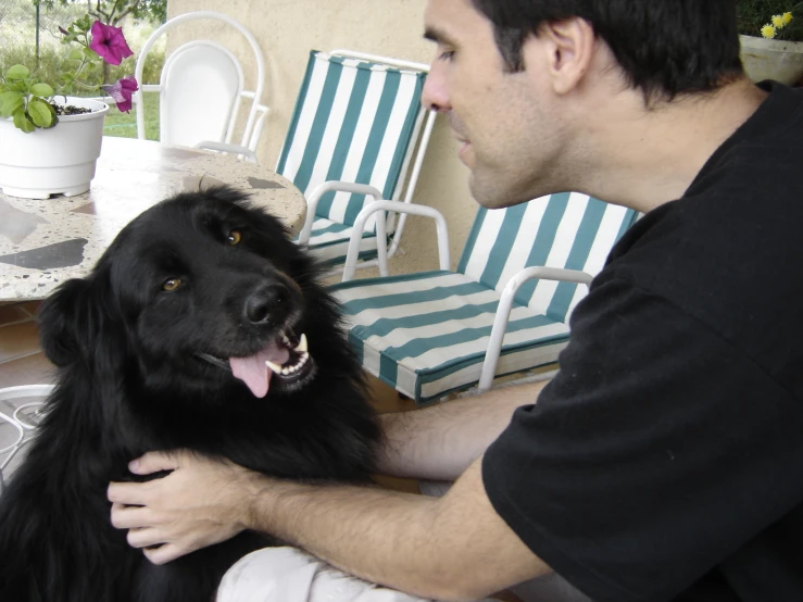 a man holding his black dog in his lap