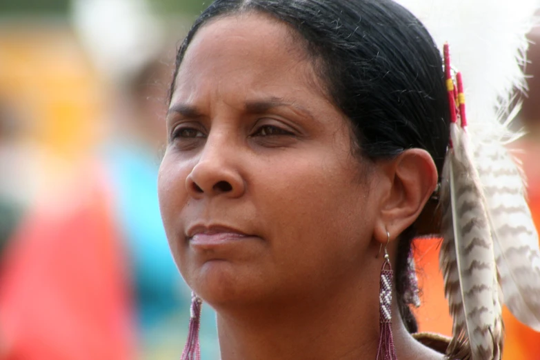 a woman wearing an indian headdress with a feather in her hand