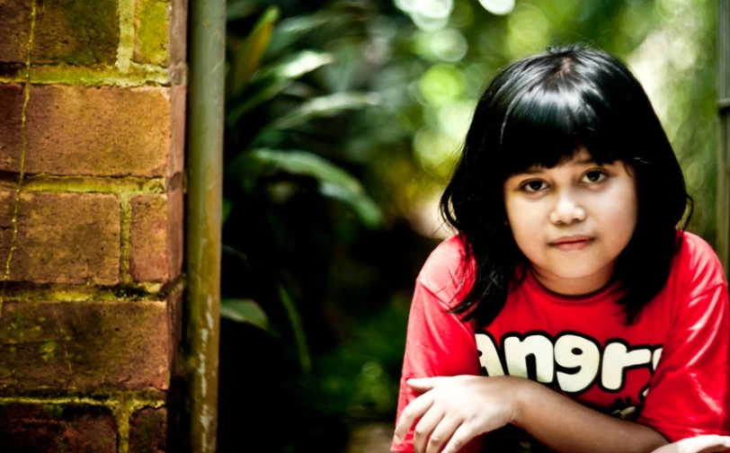 a girl wearing a shirt that reads no more sitting outside