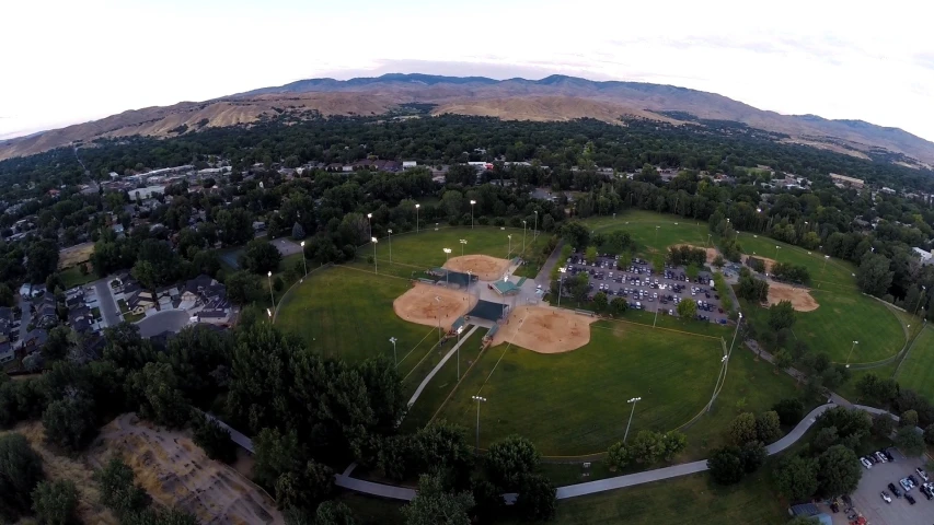 an aerial view of a baseball field with trees on the right side